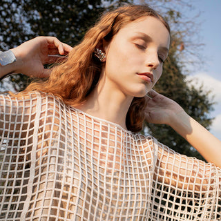 woman with red hair, earrings and a mesh blouse